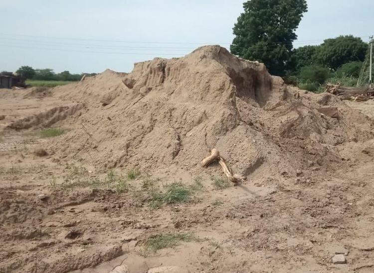 खेत में जमा पड़ी मिट्टी जिसे कुएं के चारों तरफ भरने को लेकर प्रशासन कुछ नहीं कर रहा।