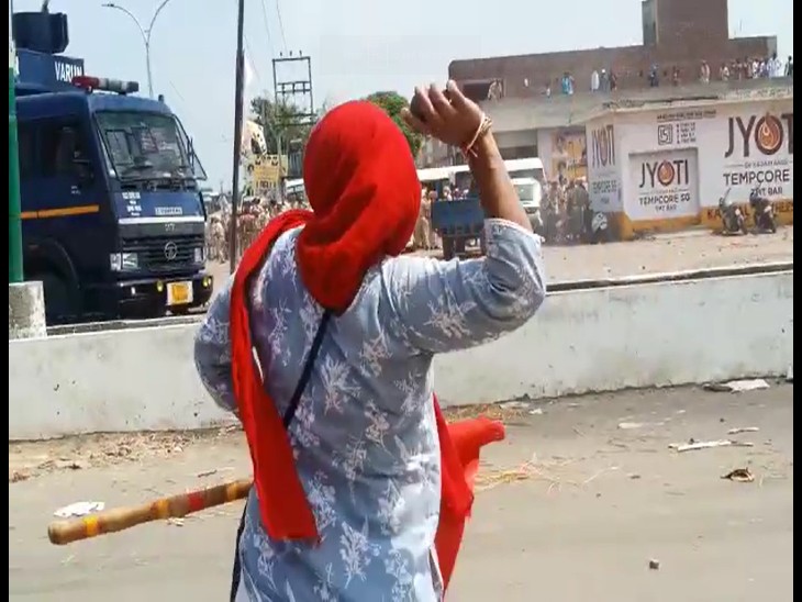 पुलिस की गाड़ी पर पत्थर फेंकती महिला।