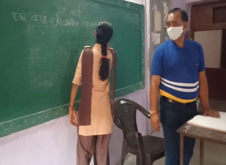 शिक्षक बाबूलाल जो बोल रहे हैं उसे बोर्ड पर लिखती छात्रा।