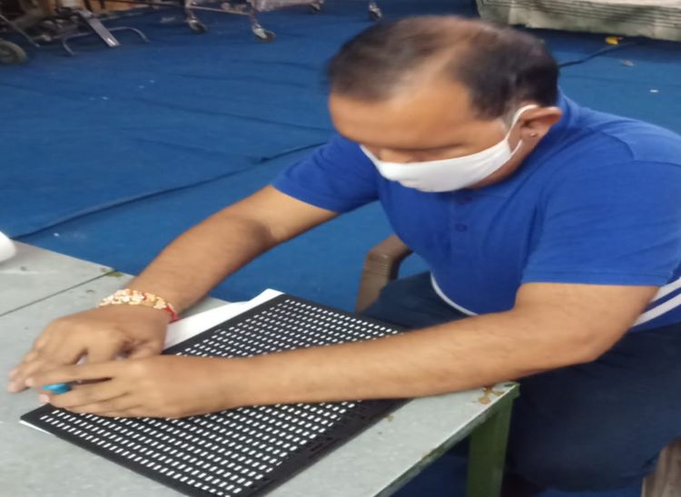 ब्रेल लिपि से लिखते हुए शिक्षक।
