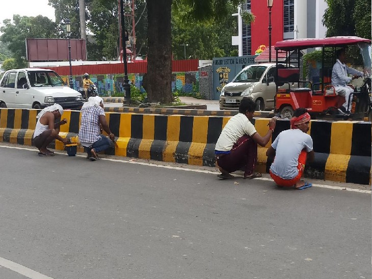 हाईकोर्ट रोड पर डिवाइडर पर रंग-रोगन करते मजदूर।