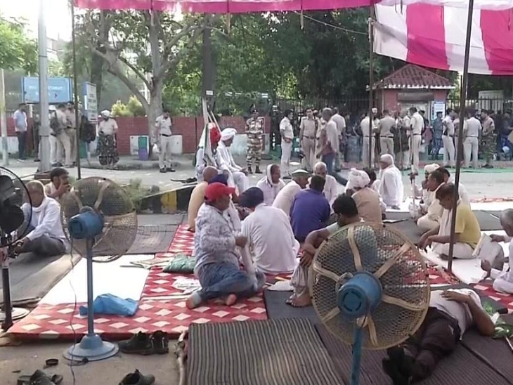 Farmers and farmer leaders resting in front of a fan at the protest site.