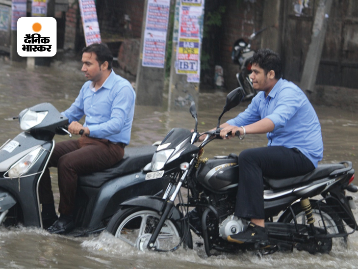 अमृतसर में हाथी गेट के पास बारिश के पानी से गुजरते बाइक सवार।