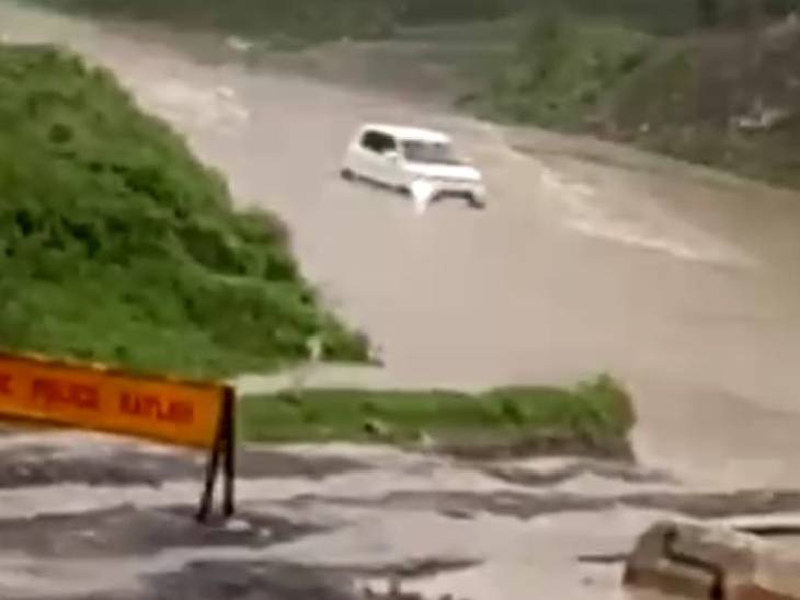 पानी के तेज बहाव में बहती कार।