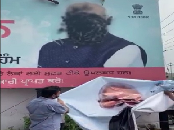 प्रधानमंत्री नरेंद्र मोदी के कालिख लगे पोस्टर को हटाते हुए भाजपा कार्यकर्ता