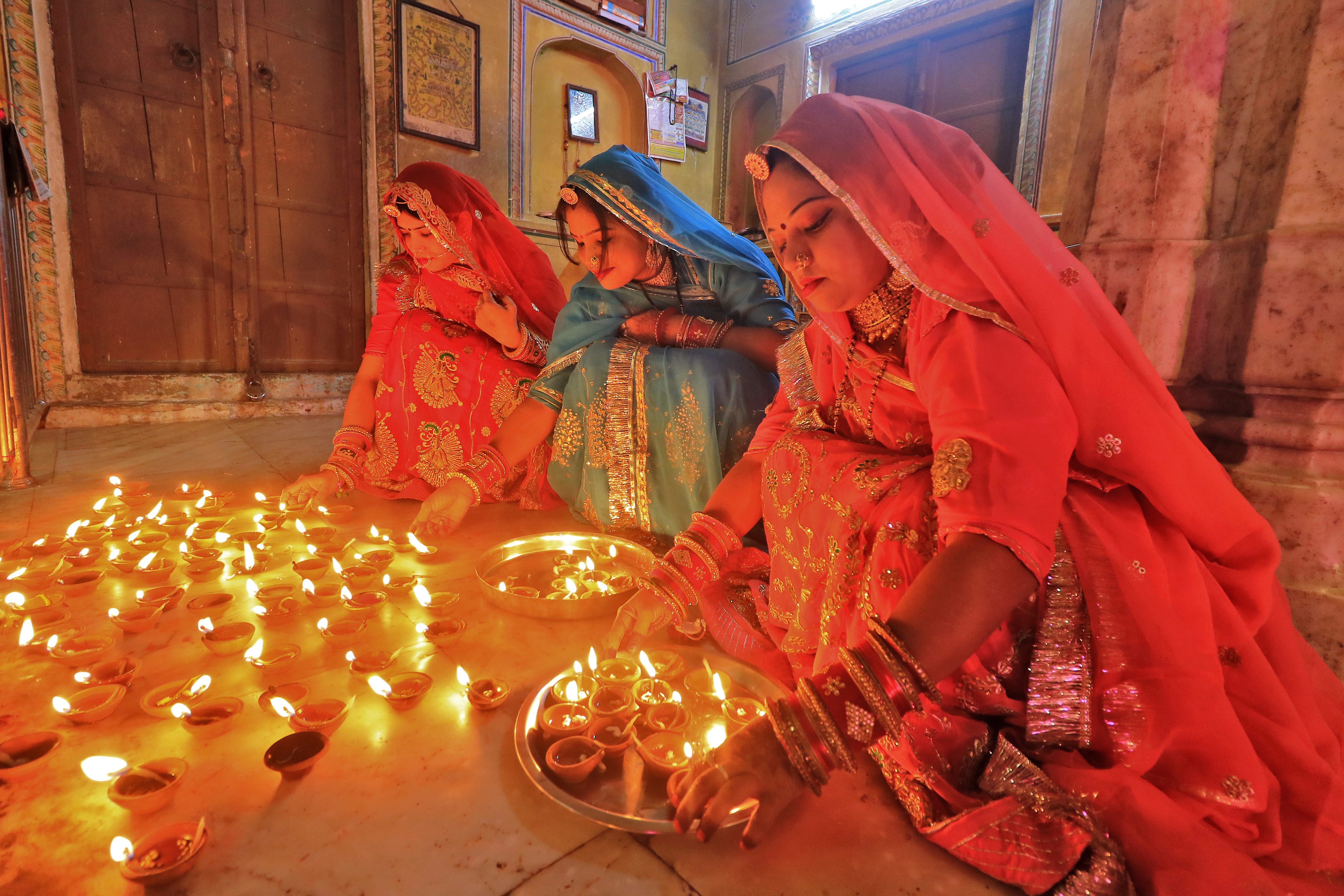 राजस्थान के जयपुर में रामचंद्रजी मंदिर में दीये जलाती महिलाएं।