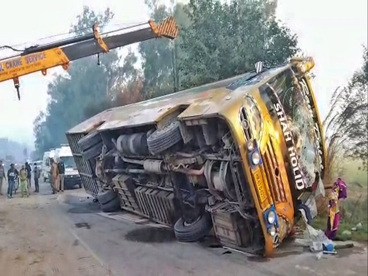 क्रेन की मदद से पुलिस की गाड़ी व कार पर पलटी बस को उठाते हुए