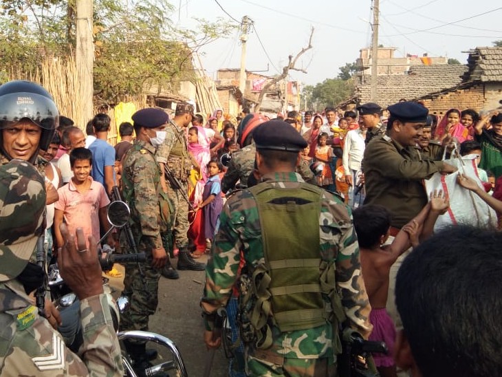 बच्चों के बीच चॉकलेट बांटते पुलिसकर्मी।
