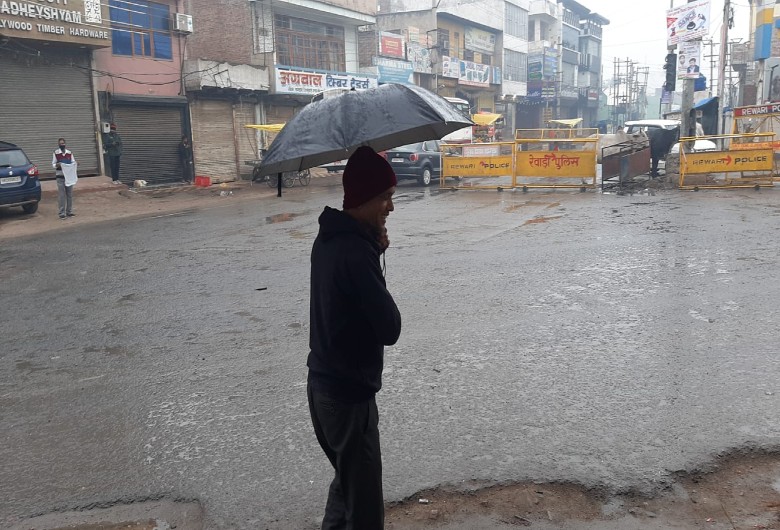बारिश के बीच छाता लेकर गुजरता व्यक्ति।