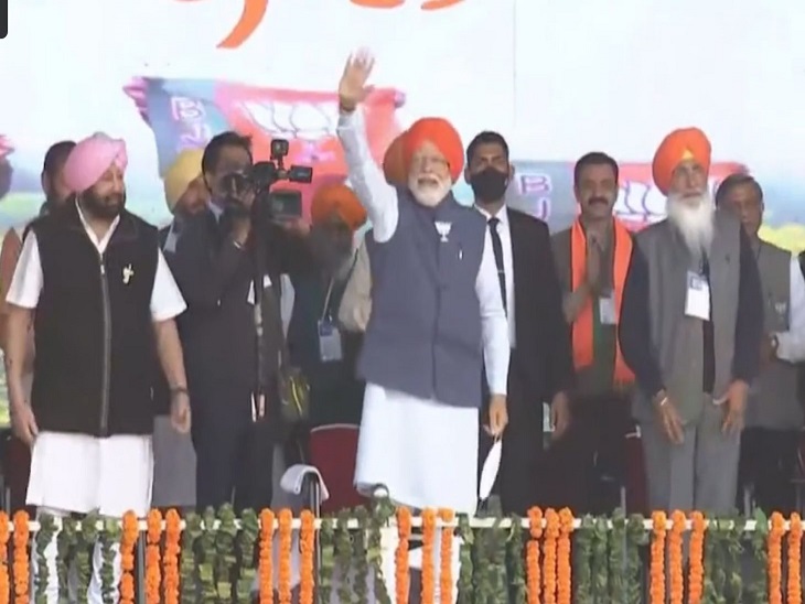 स्टेज पर लोगों का अभिवादन करते प्रधानमंत्री नरेंद्र मोदी