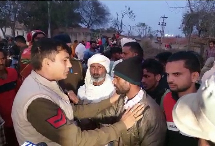 परिजनों को समझता पुलिस कर्मचारी।