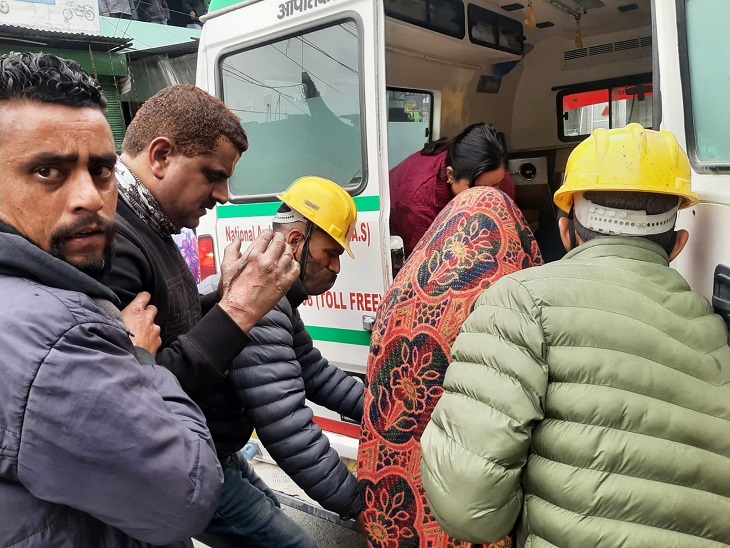 गांधीनगर में आग से झुलसी महिला को अस्पताल ले जाते परिजन और अन्य।