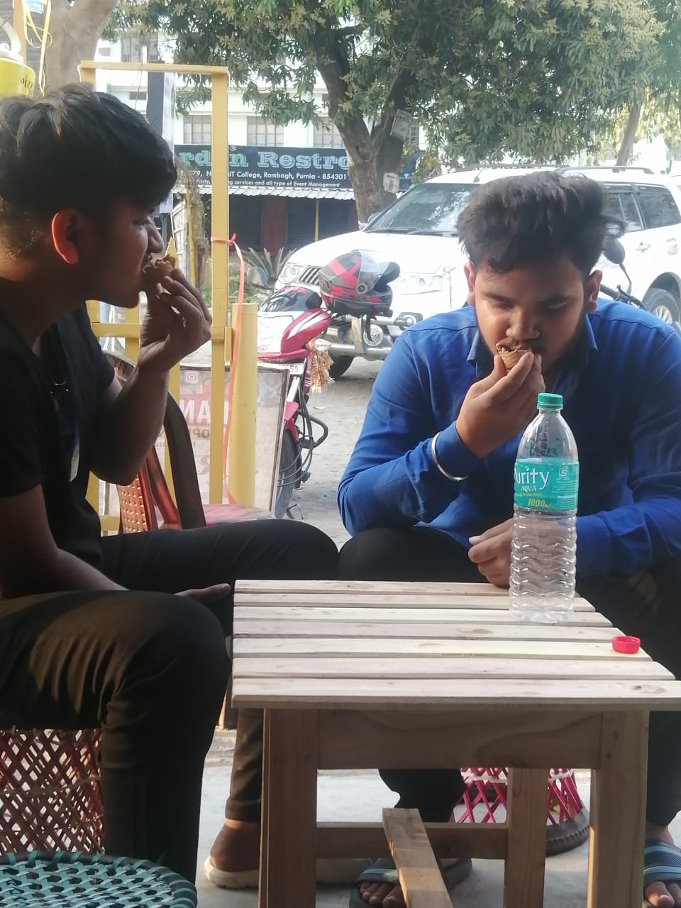 चाय पीने के बाद कुल्हड़ को खाते दो युवा।