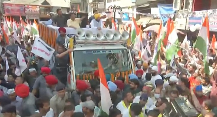 रोड शो में उत्साहित लोगों को शांत रहकर आगे बढ़ने के लिए कहते केजरीवाल।