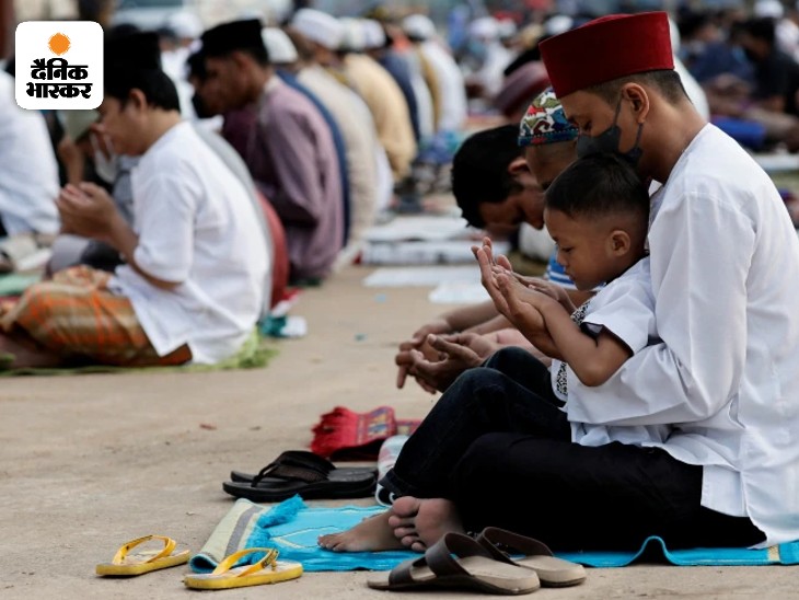इंडोनेशिया के जकार्ता में बच्चे को गोद में लेकर नमाज पढ़ता आदमी।