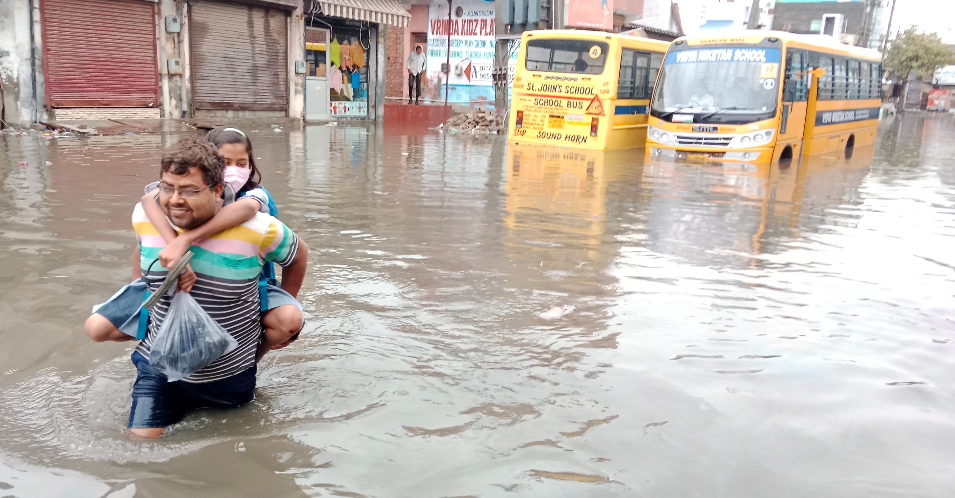 बारिश के कारण हुए जलभराव से जवाहर कॉलोनी में बच्ची को स्कूल छोड़ने की मशक्कत करता शहरवासी