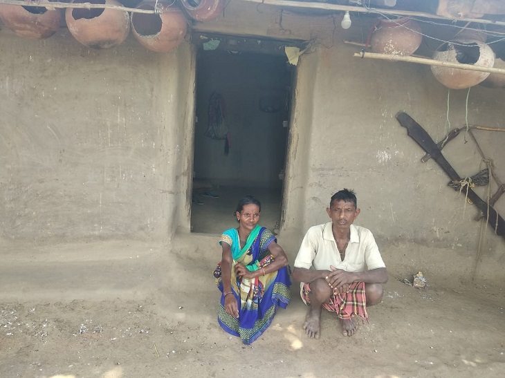 अपनी झोपड़ी के बाहर बैठे मीना के माता-पिता। दोनों मजदूरी करते हैं।