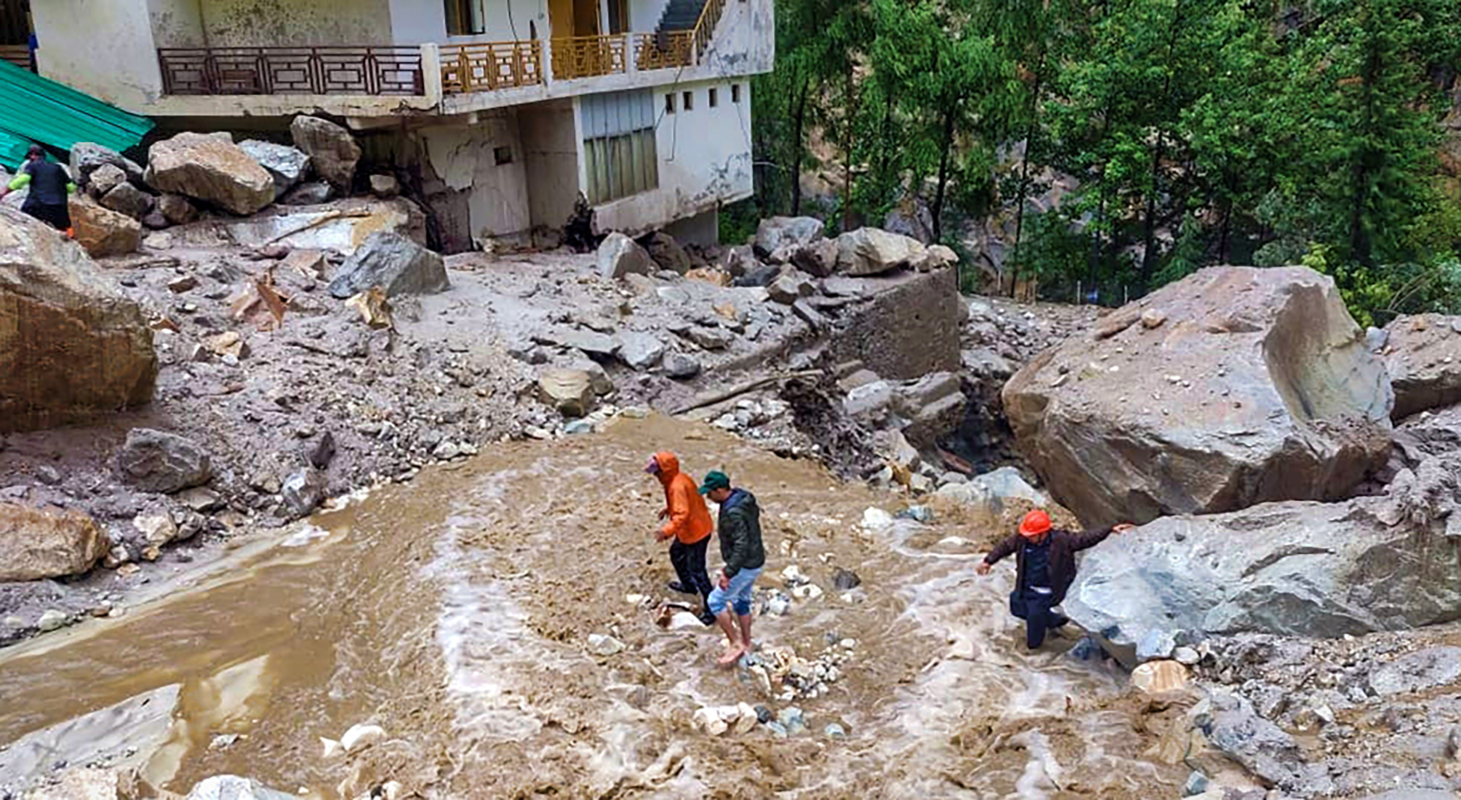 कुल्लू जिले की मणिकरण घाटी में बुधवार को बादल फटने के बाद बाढ़ वाले इलाके को पार करते लोग। यहां भारी बारिश और अचानक आई बाढ़ की अलग-अलग घटनाओं में 7 लोगों के मारे जाने की आशंका है।
