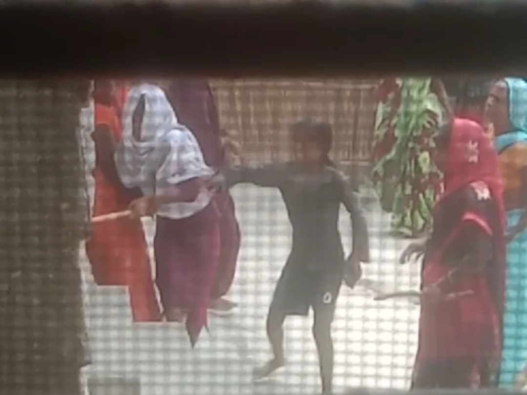 दरवाजे पर लाठी से वार करती महिलाएं।