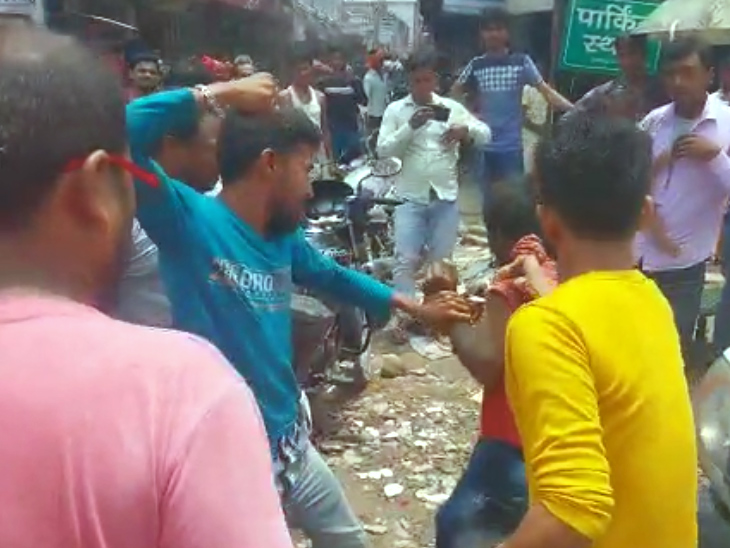 युवक की पिटाई करते लोग।