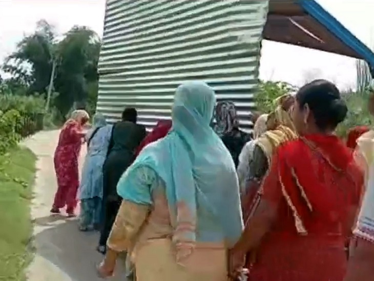 शराब ठेके के खोखे को फेंकने के लिए ले जाती महिलाएं।