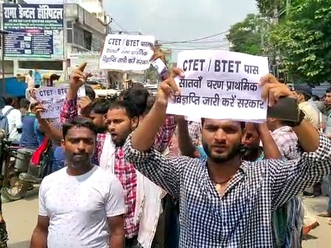पोस्टर के साथ प्रदर्शन करते अभ्यर्थी।