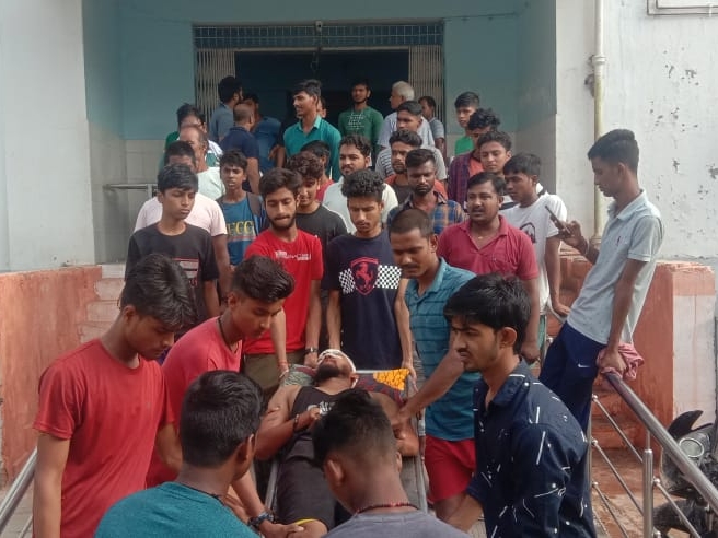 जख्मी युवक को अस्पताल ले जाते लोग।