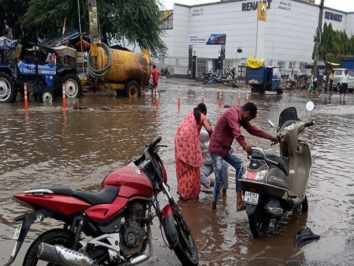 बाटा चौक पर हुए गड्ढे में गिरकर घायल हुआ स्कूटी चालक, उसे उठाती महिला