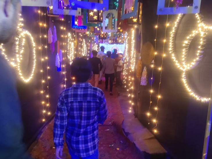 रंग बिरंगी लाइटों से सजी गलियों से होकर झांकी देखने जाते बच्चे व लोग