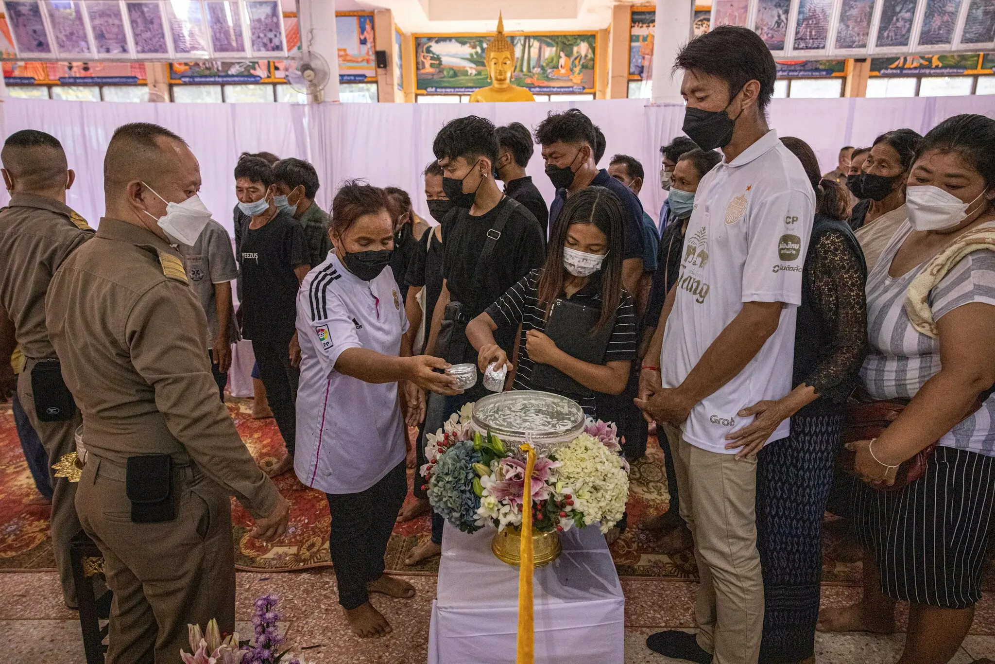 परिजन मृत शव पर दानधर्म की चीजें जैसे चावल, खिलौने और फूलों के गुलदस्ते चढ़ा रहे हैं।