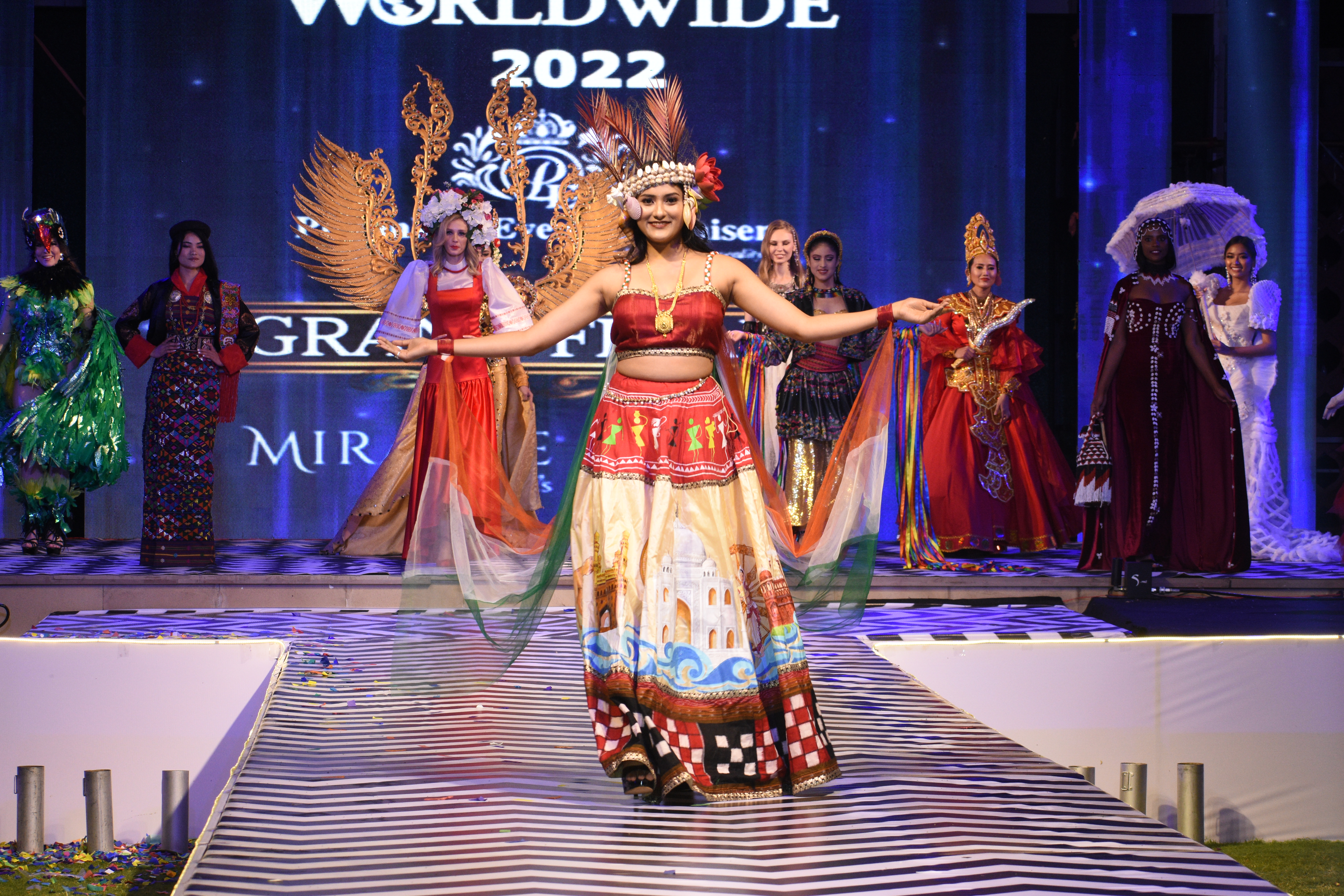 इंडिया की मॉडल ने इस राउंड के लिए लहंगे पर इंडिया के फेमस मॉन्यूमेंट्स सरपर आदवासी अटायर , ओर दोनों हाथों में तिरंगे की चुनरी लहराते हुए रैंप पर अपना जलवा बिखेरा।