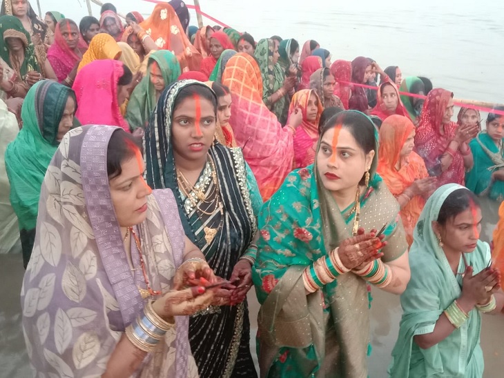 बक्सर के गंगा घाट पर उगते हुए सूर्य को अर्घ्य देने के लिए नदी में खड़े होकर इंतजार करती महिलाएं।