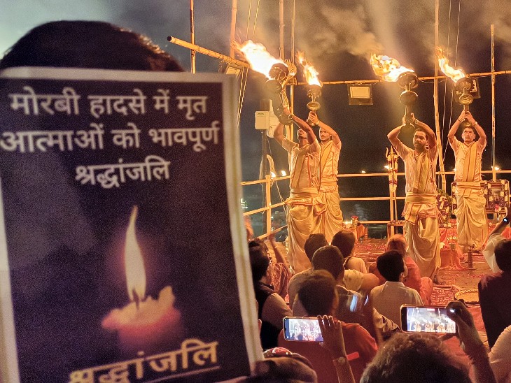 वाराणसी के दशाश्वमेघ घाट पर गंगा आरती के दौरान मोरबी हादसे में जान गंवाने वालों को श्रद्धांजलि देते श्रद्धालु।