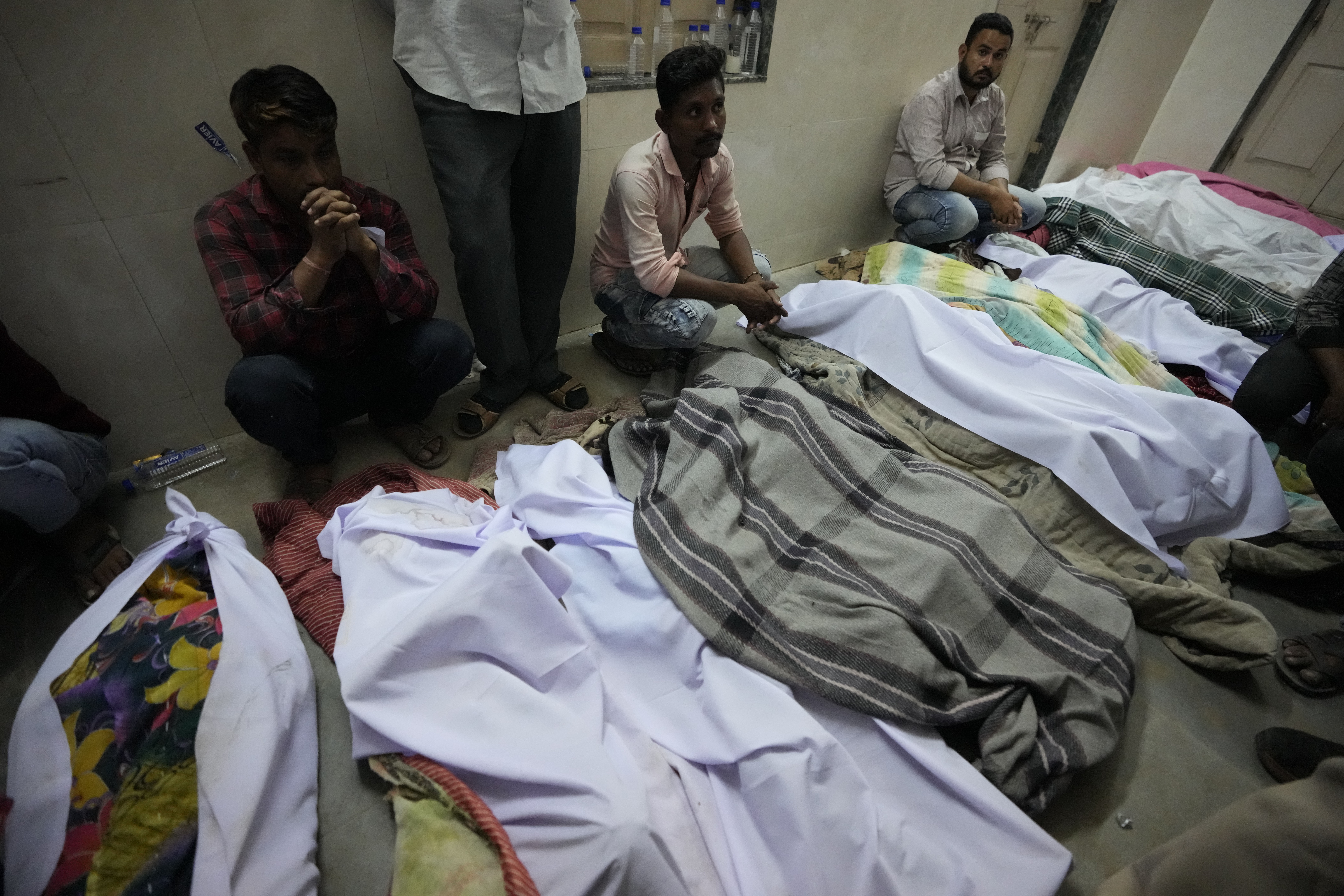 पुल हादसे में मारे गए लोगों के शव। पास में बैठे उनके परिजन। रविवार रात तक कई लोग शवों में अपनों को तलाशते रहे।