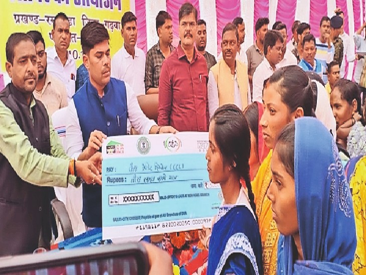 कार्यक्रम में लाभुक को चेक देते डीसी और अन्य। - Dainik Bhaskar