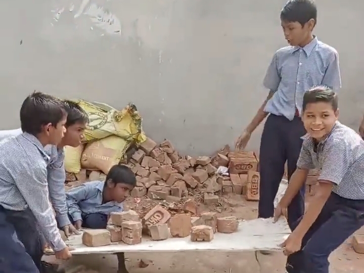શાળામાં ઇંટો ઉપાડતા બાળકો.