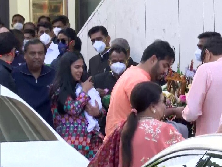 अपने बच्चे को गोद में ले जातीं ईशा अंबानी पीरामल। उनके पीछे पिता मुकेश अंबानी।