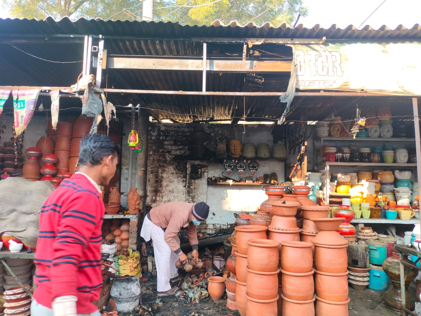 दुकान में आग लगने के बाद सामान संभालता दुकान मालिक।