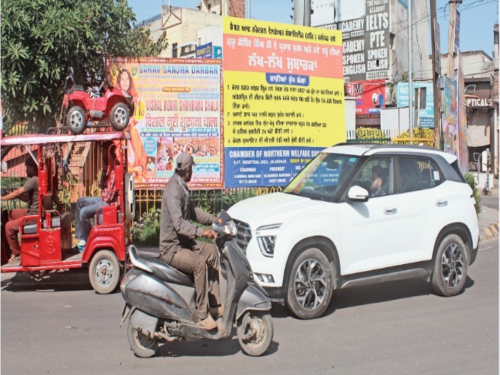 दोआबा चौक में लगे होर्डिंग्स को देखता एक्टिवा सवार। इसी तरह ध्यान भटकने से अक्सर हादसे हो जाते हैं।-भास्कर - Dainik Bhaskar