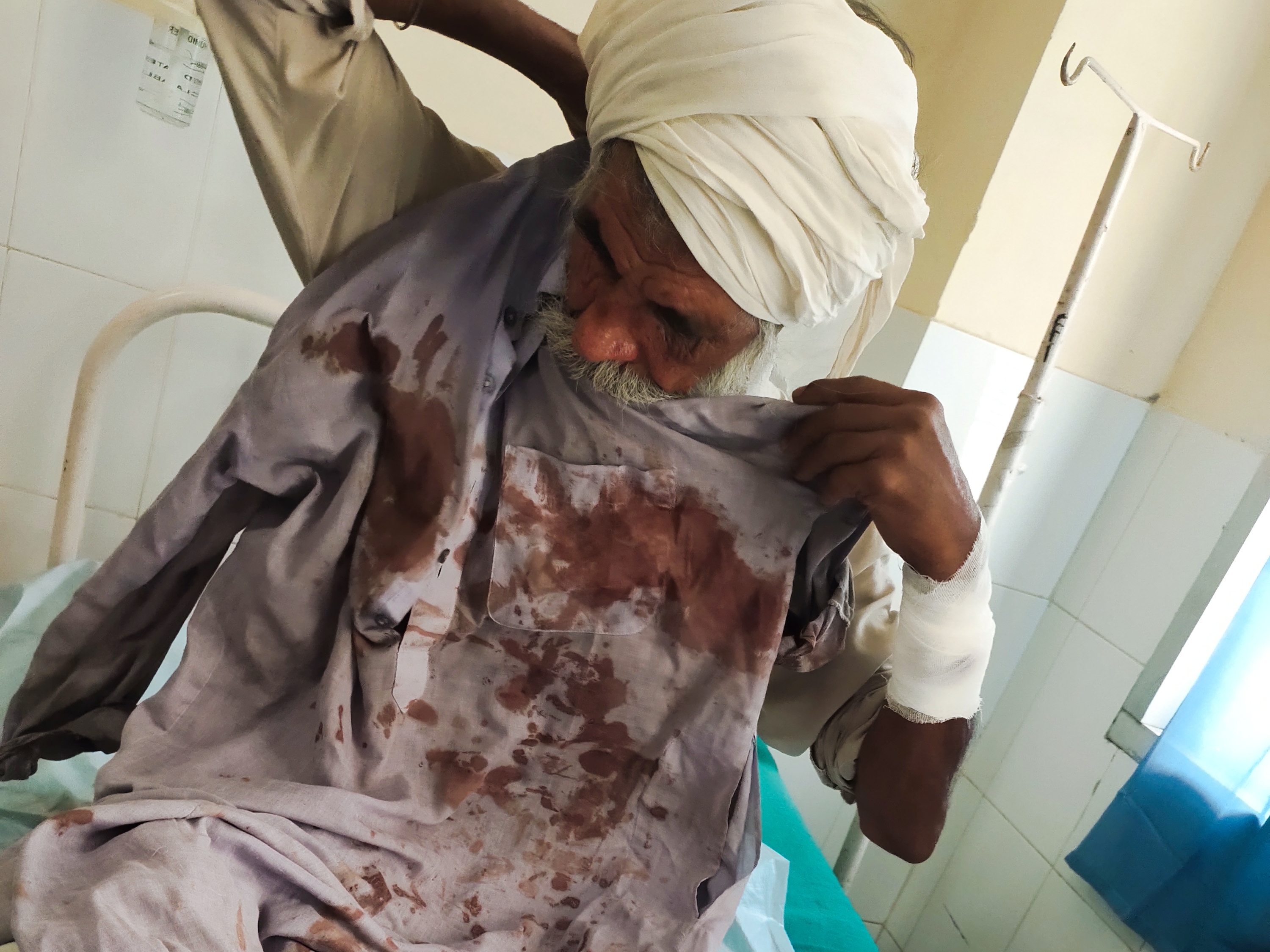 खून से लथपथ कपड़े दिखाता पीड़ित बुजुर्ग।