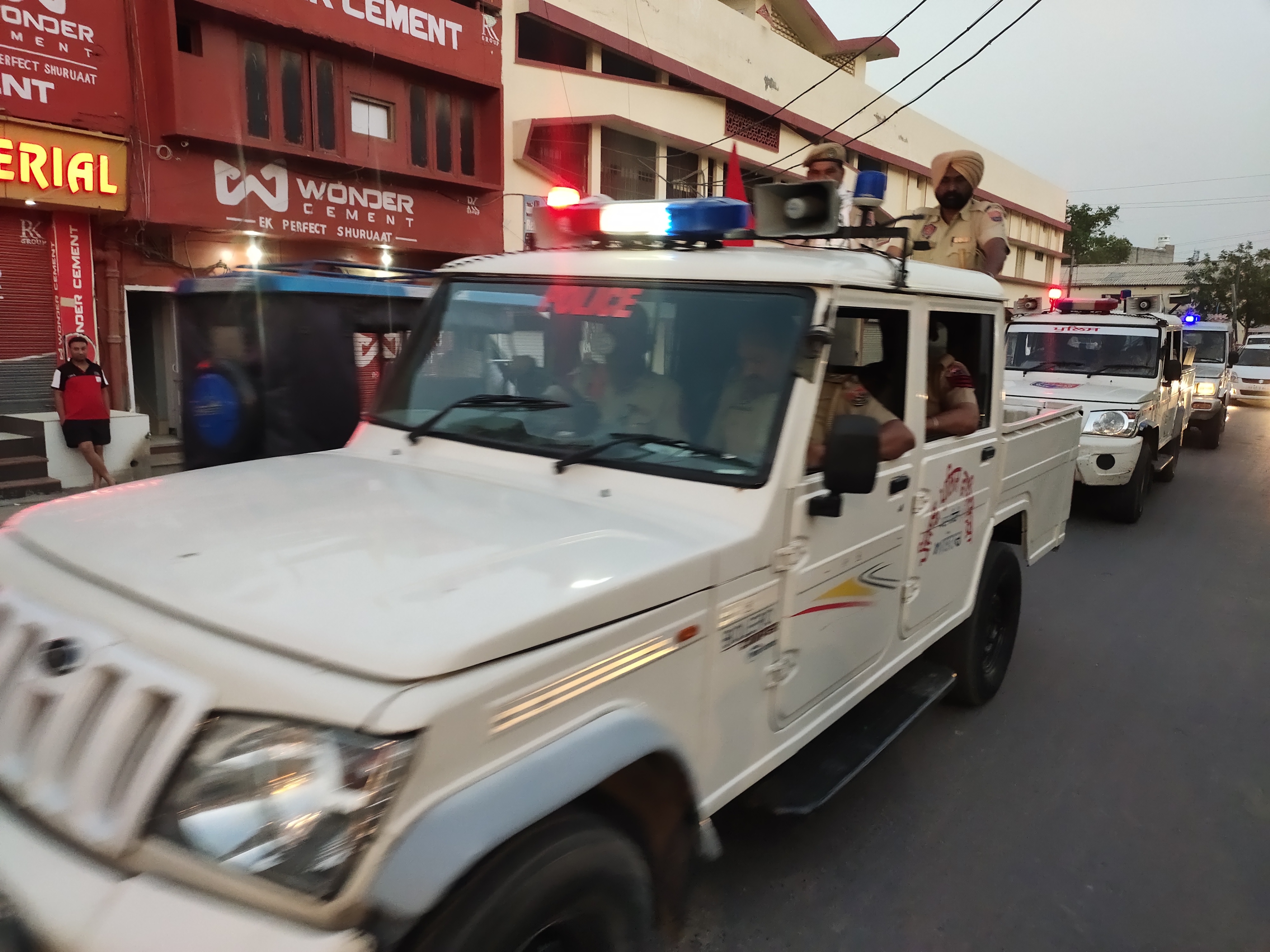 शहर में फ्लैग मार्च निकालते पुलिस वाहन।