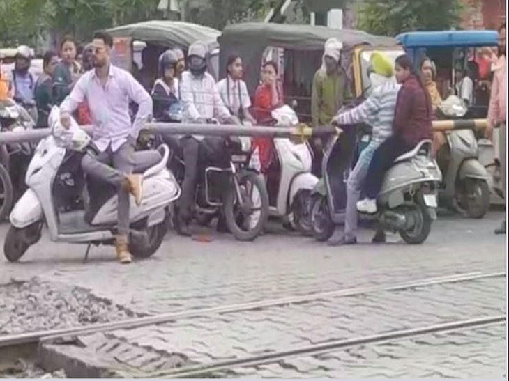 फाटक के अंदर खड़े दोपहिया वाहन चालक।