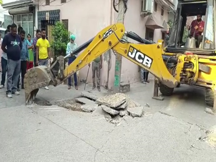सड़क पर दरारें आने के बाद मौके पर खुदाई करवाते निगम अधिकारी।