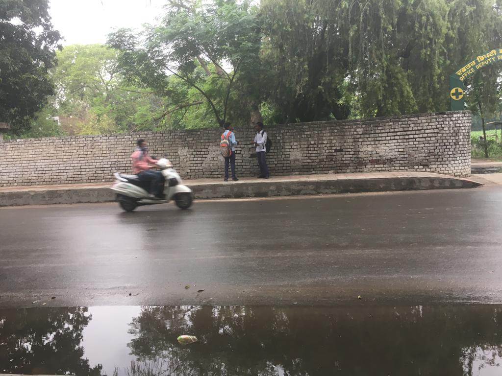 फरीदकोट में हो रही बारिश में गुजरता स्कूटी चालक।