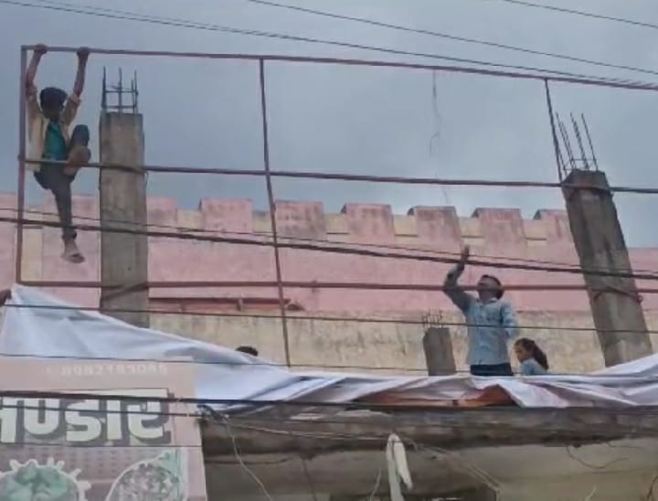 थिएटर के बाहर बिल्डिंग में लगे पोस्टर को निकालते हुए लोग।