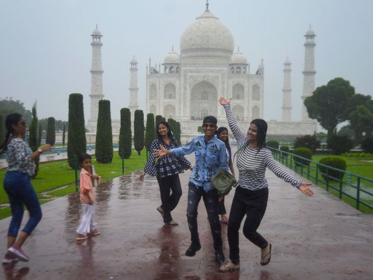 आगरा में ताजमहल के सामने बारिश में भीगते टूरिस्ट।