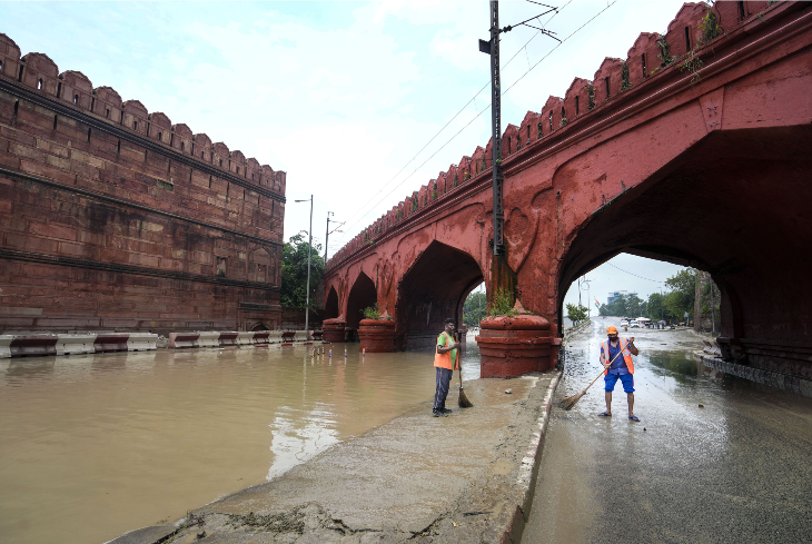 यमुना का पानी घटने के बाद लाल किले के पीछे के सड़क की सफाई करते दिल्ली म्युनिसिपल कॉर्पोरेशन के कर्मचारी।