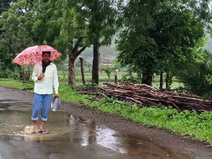 खैरागढ़ जिले में भारी बारिश होने से सड़कों पर पानी भरा रहा, पानी से बचने के लिए रोड पर छतरी लेकर खड़ा हुआ युवक।