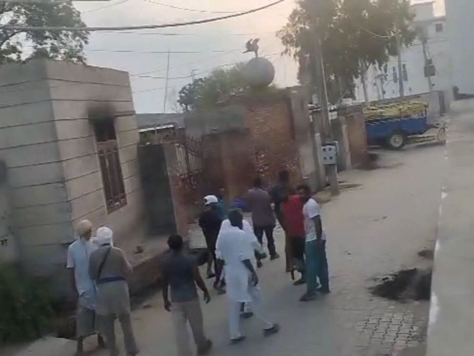 युवक की धारदार हथियार से हत्या: दो पक्षों में खूनी संघर्ष 2 गांव में मृतक के घर के बाहर खड़े लोग।