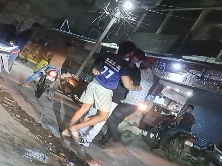 बदमाश का हाथ पीठ पर है और युवक के शरीर में उसने चाकू धंसा रखा है।